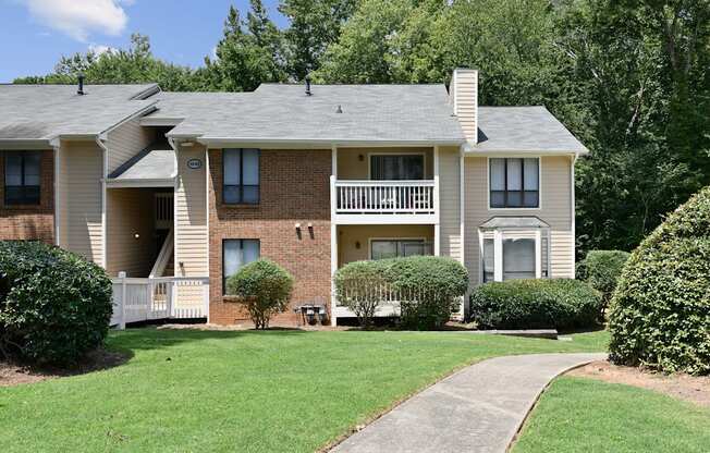 an apartment building with a lawn and a sidewalk in front of it