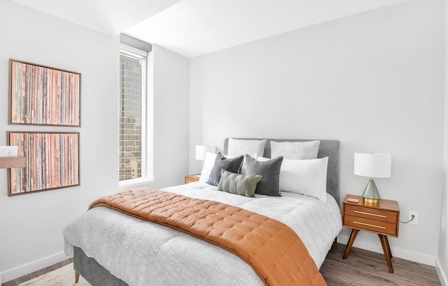 A bedroom with a bed, nightstand, and a picture on the wall.