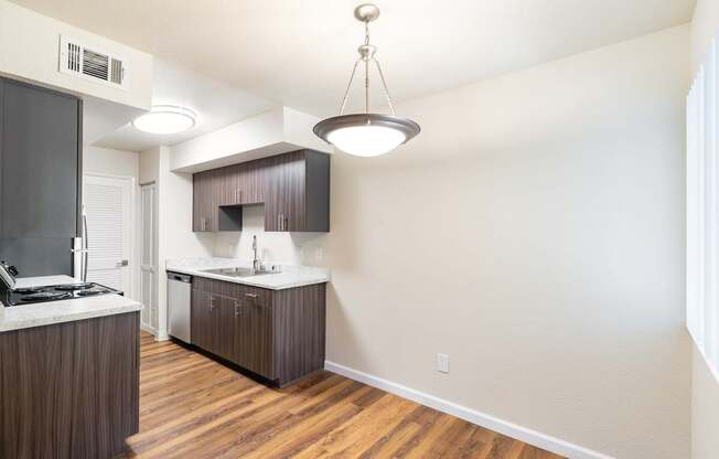 A kitchen with wooden floors and a white wall.