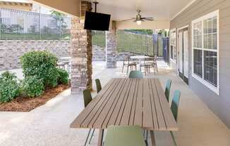 A patio with a table and chairs and a TV on the wall.