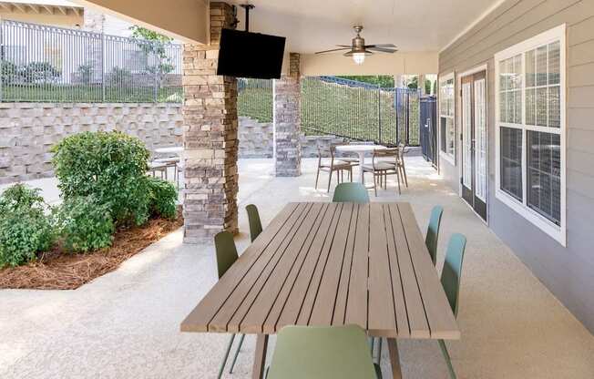 A patio with a table and chairs and a TV on the wall.
