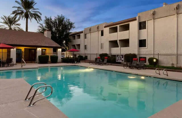 A swimming pool in a resort with a building in the background.
