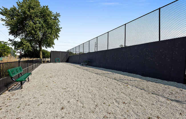 A park with a bench and a fence.