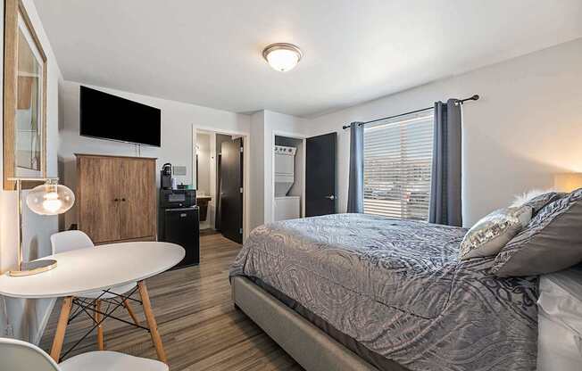 A bedroom with a bed, a desk, and a chair.