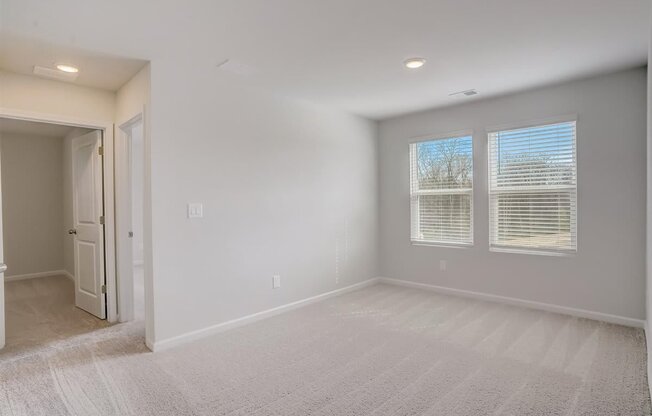 A room with a carpeted floor and a window with blinds.