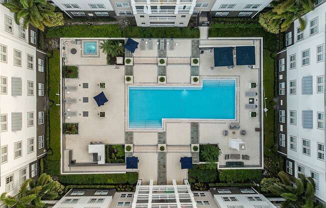A swimming pool is surrounded by a patio and a small garden.