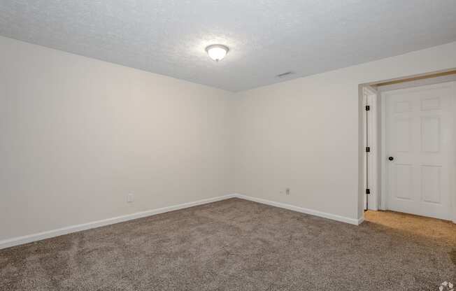 A room with a carpeted floor and a white door.