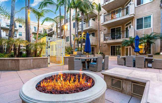 a fire pit in the middle of a patio with tables and umbrellas