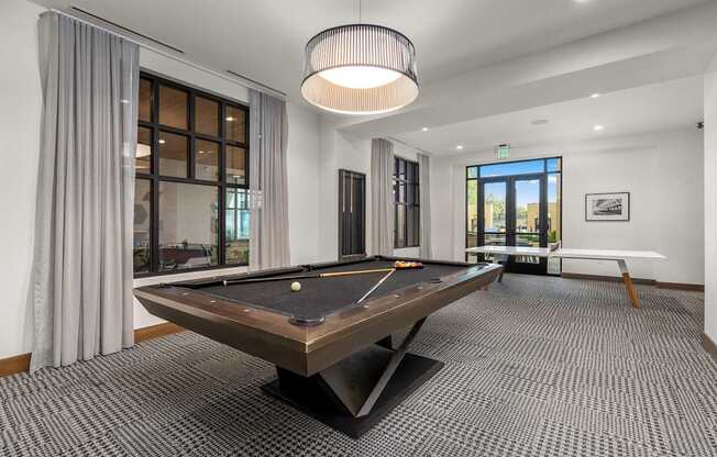 A pool table is in the middle of a room with a carpeted floor.