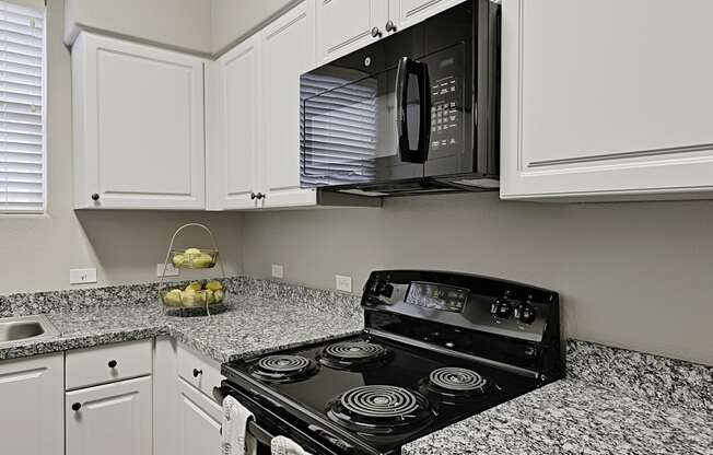 a kitchen with white cabinets and a stove and a microwave