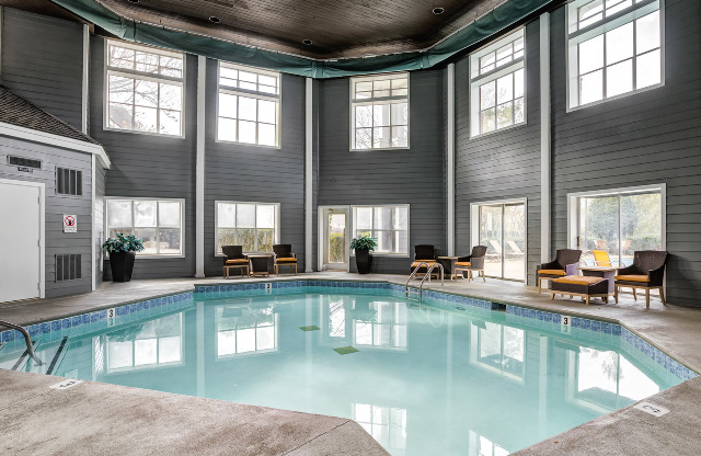 Indoor pool at our apartments in Nashville, TN, featuring cushioned chairs with small tables and a large octagonal pool.
