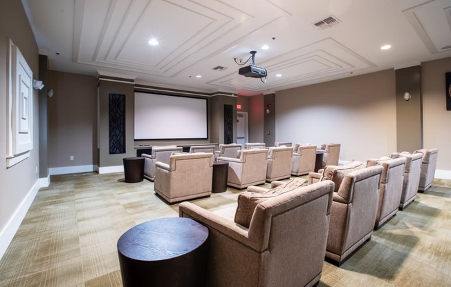 a large movie room with chairs and a projector screen on the wall