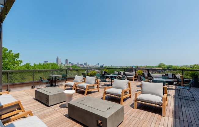 an outdoor deck with lounge chairs and fire pits with a view of the Cleveland skyline at TREO Apartments, Cleveland, 44116