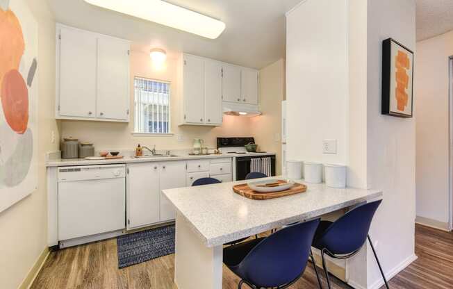 a kitchen with white cabinets and a white table with blue chairs at Renaissance Park Apartments, California, 95618