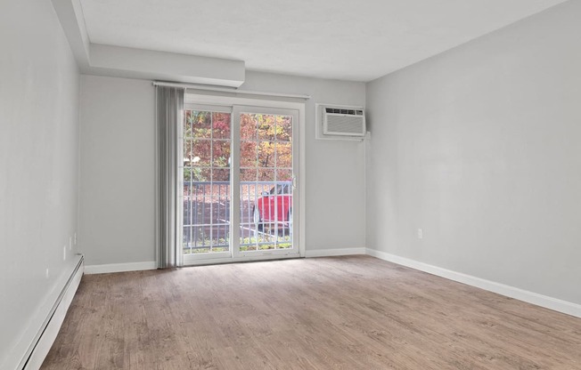 Empty living room with a sliding glass door to a patio  at the River, Manchester, 03102