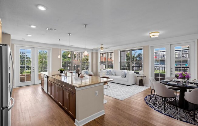 a kitchen with a center island next to a living room with a couch and a table