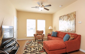 A living room with a red couch and a ceiling fan.