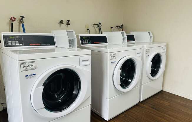 a group of washing machines and dryers in a laundry room