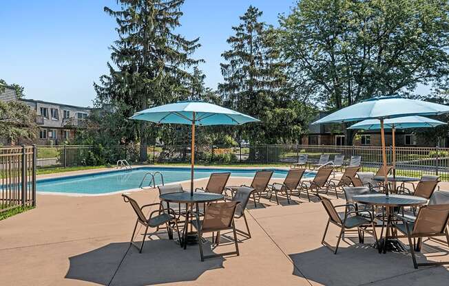 A poolside table set up with chairs and umbrellas.