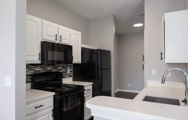 a kitchen with black appliances and white cabinets and a sink