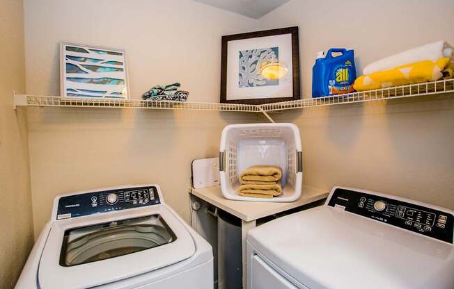 A laundry room with a washer and dryer and a basket of towels.