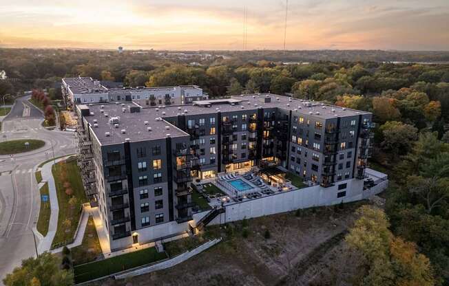 A modern apartment complex with a pool and surrounded by trees.