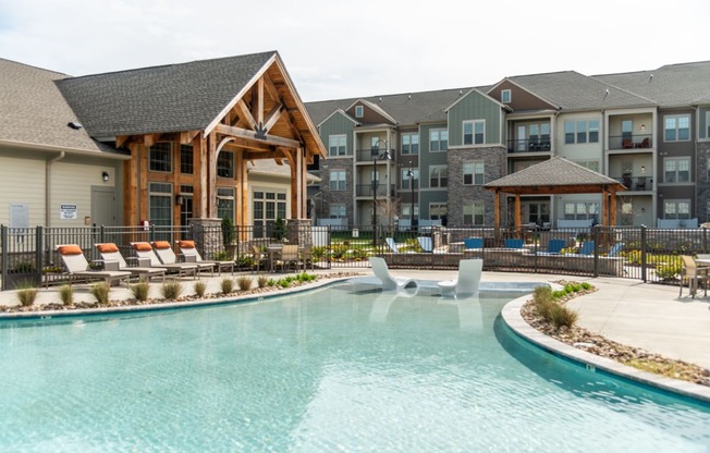 a swimming pool with lounge chairs and a lazy river in front of an apartment building at The Whitworth, Virginia