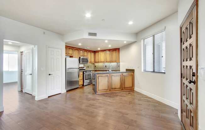 an empty kitchen with wooden cabinets and a stainless steel refrigerator