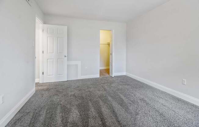 A room with a carpeted floor and two doors, one of which is open.