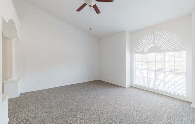 A room with a ceiling fan and carpeted floor.