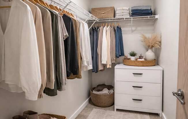 A white closet with clothes and shoes.
