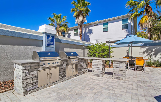 the outdoor patio has a barbecue grill and a table with umbrellas at Reserve at Temple Terrace, Temple Terrace