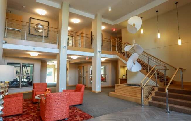 A large open space with a staircase and red chairs.