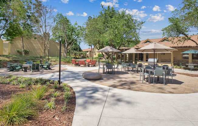 a patio with tables and chairs and umbrellas at Summerwood Apartments, Santa Clara