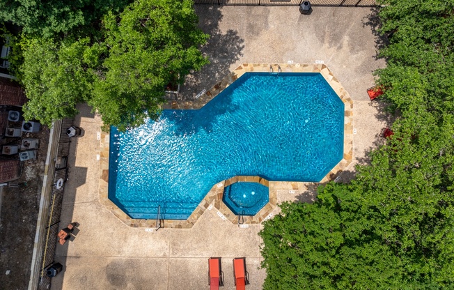 A small pool surrounded by trees and a concrete floor.