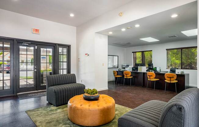 A modern office space with a green rug and a round orange ottoman.