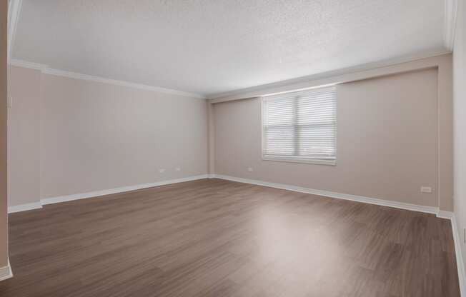 an empty living room with wood floors and a window