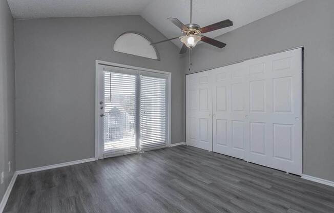 A room with a ceiling fan and a sliding glass door.