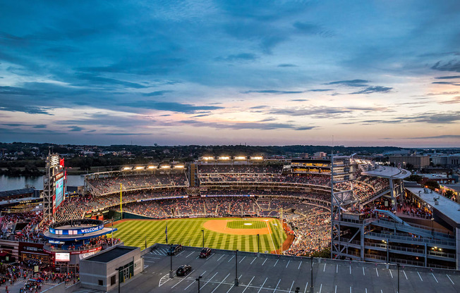 A baseball stadium is filled with fans and bathed in stadium lights.