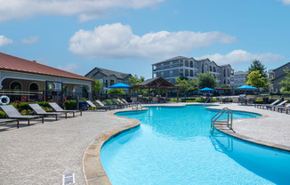 Swimming pool sundeck with lounge chairs and umbrellas with natural surround landscape