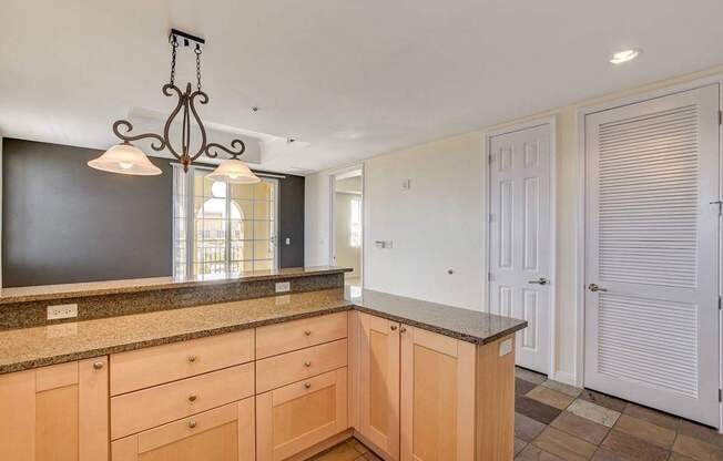 A kitchen with wooden cabinets and a hanging light fixture.