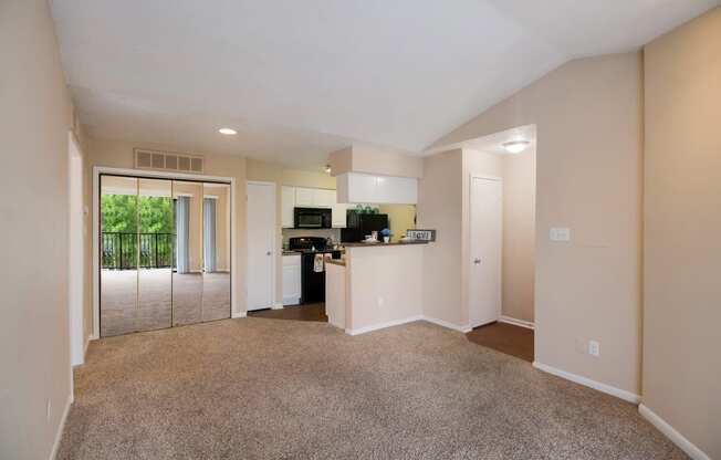 Empty living room and kitchen with a door to a balcony at The Glen at Highpoint, Dallas, TX, 75243
