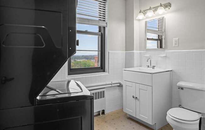 A bathroom with a toilet, sink, and a window.