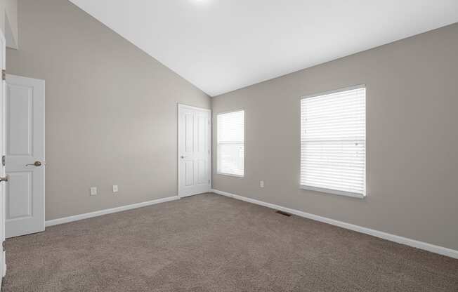 an empty living room with a door and two windows at Traditions at Slate Ridge, Reynoldsburg Ohio