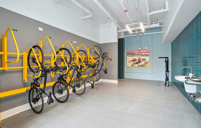 a room with several bikes hanging on a wall and a bathroom with sinks at Link Apartments® Mint Street, North Carolina, 28203