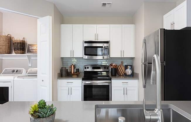 kitchen with white cabinets and stainless steel appliances at the district flats apartments in lenexa,