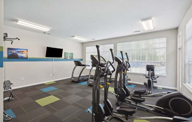 A gym with exercise equipment and a TV on the wall.