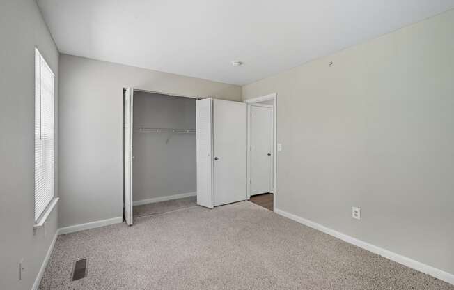 A room with a carpeted floor and a white closet with a sliding door.