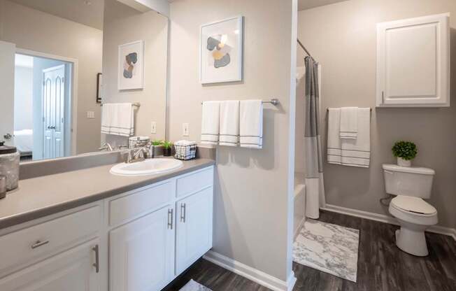 A bathroom with a white toilet, sink, and cabinets.