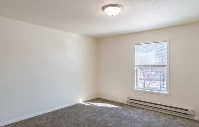 an empty room with carpet and a window. Fargo, ND Stonebridge Apartments